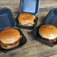 Three Wingstop Chicken Sandwiches in to-go containers on table